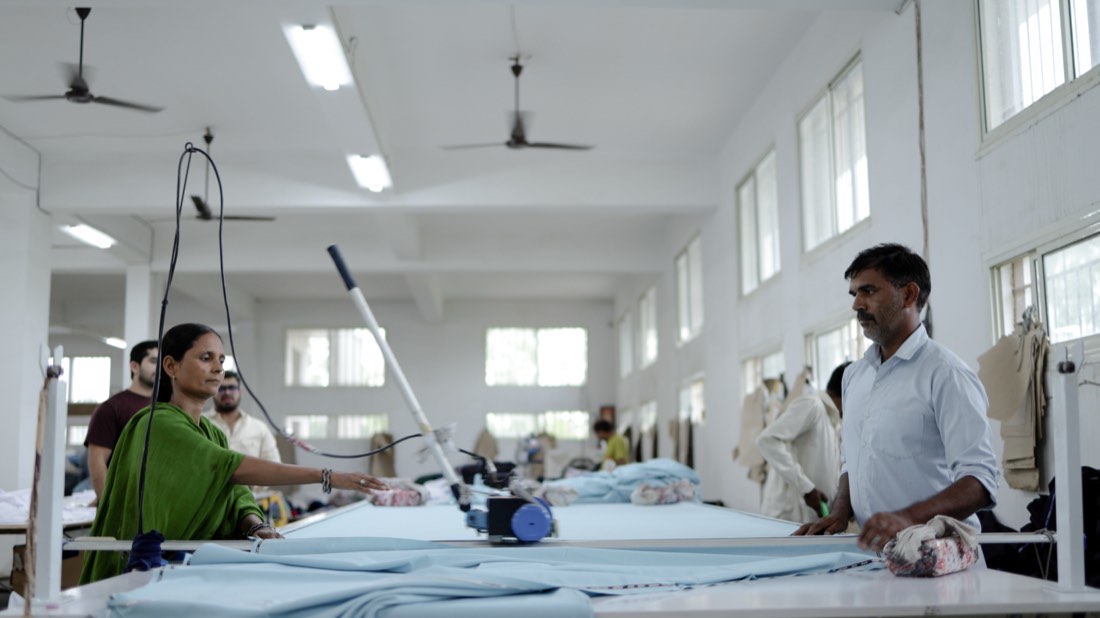 The cutting table with fabric laid out and staff working